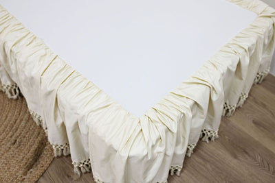 Enlarged view of a cream bed skirt with tassels.
