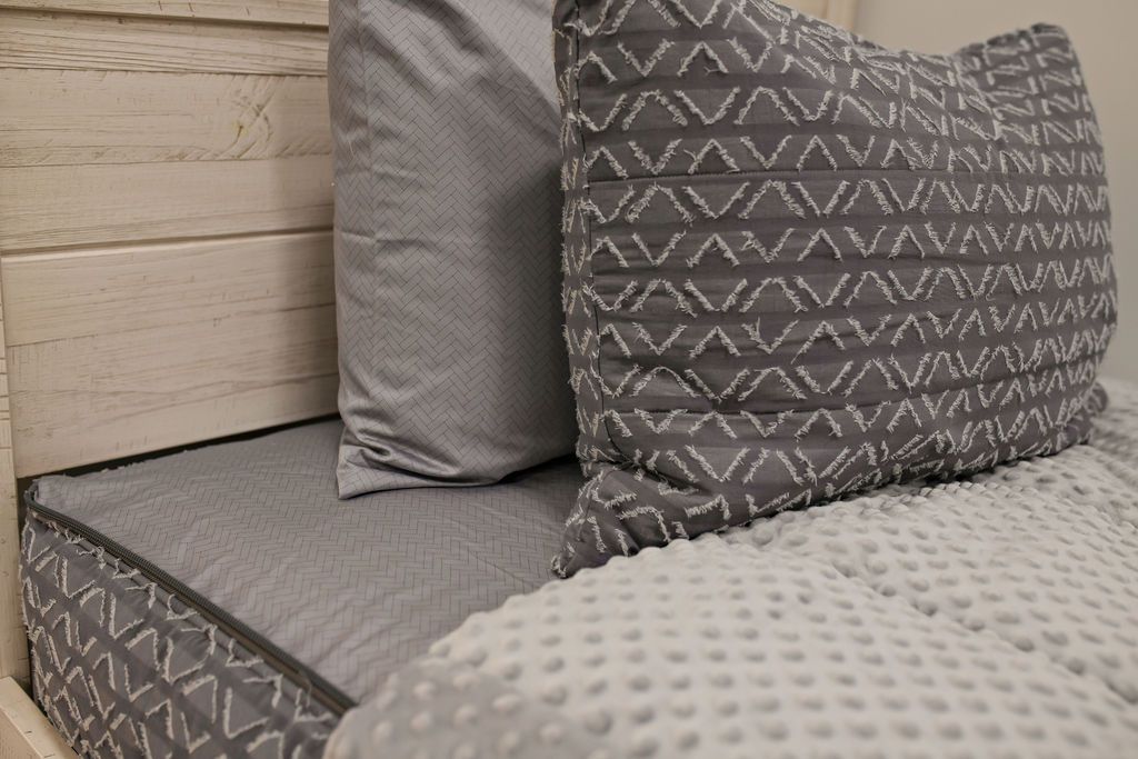 Enlarged view of a gray patterned pillowcase and a gray and white textured sham.
