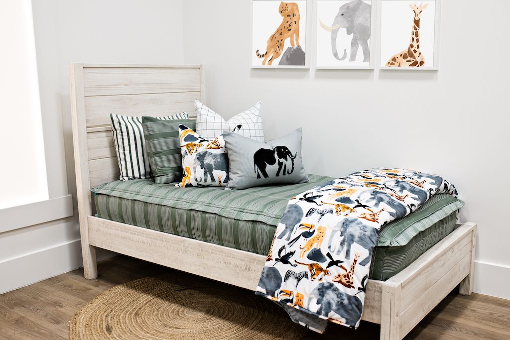twin bed with Green striped bedding with white and black grid patterned euro, safari animal print pillow, gray lumbar with embroidered elephant and safari animal print blanket