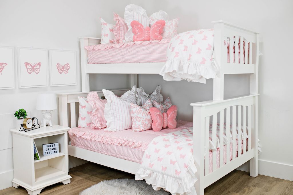 White bunk beds with a pink and white striped ruffled bedding, white and pink striped pillows, white and pink butterfly pillows, a pink butterfly shaped pillow and a white and pink butterfly blanket.  