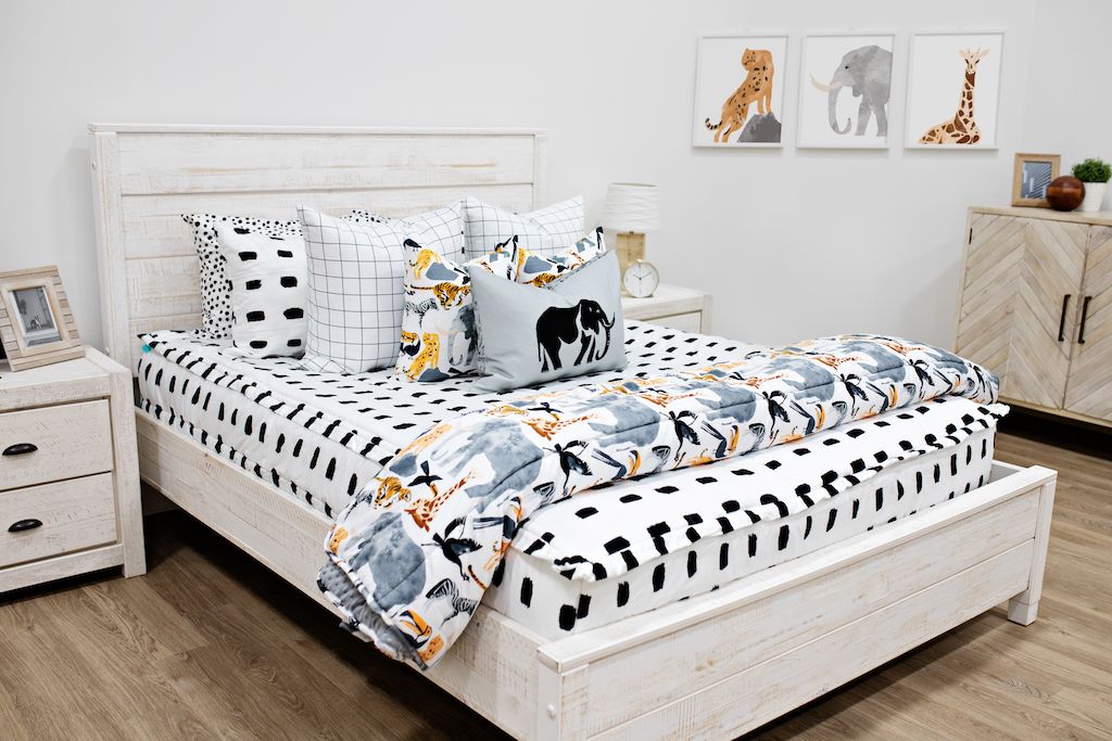 queen bed with white and black dashed bedding and white and black grid patterned euro, safari animal print pillow, gray lumbar with embroidered elephant and safari animal print blanket