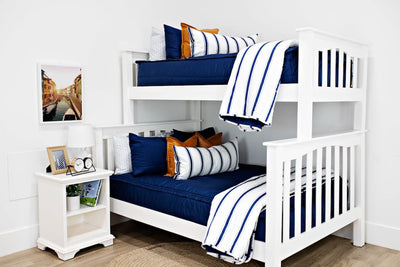 White bunk beds with navy blue bedding, medium brown leather pillows, a white and navy blue striped lumbar pillow and a white and navy blue striped blanket.  