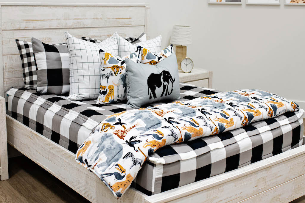 queen bed with Black and white buffalo plaid bedding white and black grid patterned euro, safari animal print pillow, gray lumbar with embroidered elephant and safari animal print blanket