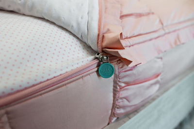 Enlarged side view of a partially unzipped blush pink ruffled bedding.