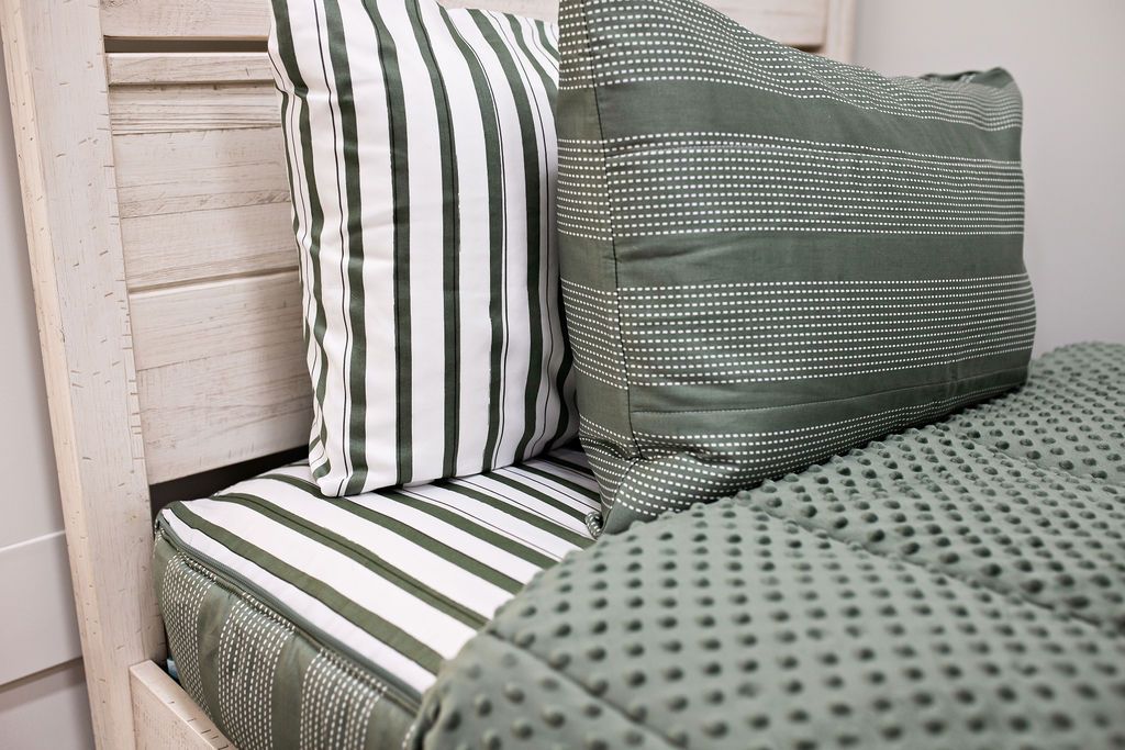 Enlarged side view of a white headboard with a white and green striped pillowcase and a sage green and white striped sham. 