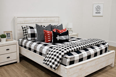 queen bed with black, white, gray buffalo print bedding with  black and white striped euros, red and white dashed pillow, black lumbar with white longboard print and black and white checkered print