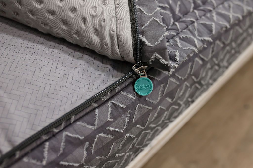 photo showing zipper edge on of gray textured bedding, gray arrow sheets and gray minky interior