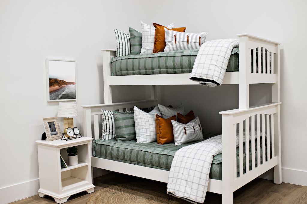bunk bed with Green striped bedding with white and black grid euro, faux leather pillows, white and black striped lumbar with faux lather buckles and white and black grid pattered blanket