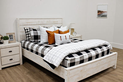 queen bed with black and white buffalo plaid bedding and white and black grid euro, faux leather pillows, white and black striped lumbar with faux lather buckles and white and black grid pattered blanket
