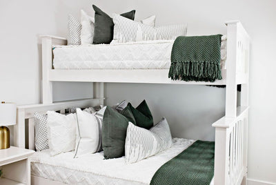 bunk bed with White bedding with texturized diamond design with moss green corduroy euro, white euro with moss green lines, white XL lumbar with moss green stitching and moss green knitted chenille throw with tassels