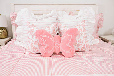 Enlarged view of a bed with pink and white striped ruffled bedding, white and pink striped pillows, white and pink butterfly pillows, and a pink butterfly shaped pillow.