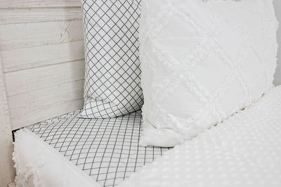 Side view of white pillow sham with textured diamond design in repeating pattern and white pillowcase with moss green diamond design in repeating pattern