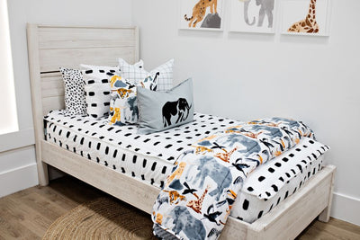 twin bed with white and black dashed bedding with white and black grid patterned euro, safari animal print pillow, gray lumbar with embroidered elephant and safari animal print blanket