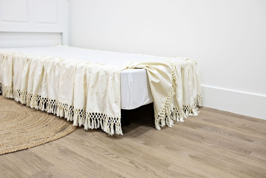 Enlarged view of a cream bed skirt with tassels.