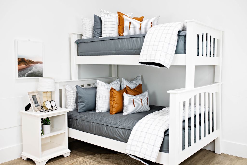 bunk bed with gray zipper bedding and white and black grid euro, faux leather pillows, white and black striped lumbar with faux lather buckles and white and black grid pattered blanket