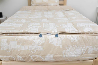 The foot of a bed made with light tan cars kids zipper bedding showing where the two zippers are located.