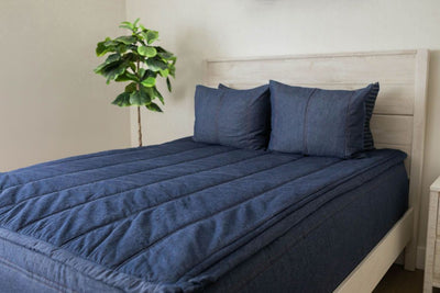 A bed made with dark denim blue zipper bedding and matching pillows.