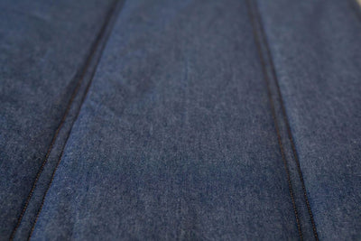A close up view of the double stitched quilting detail on dark denim blue zipper bedding.