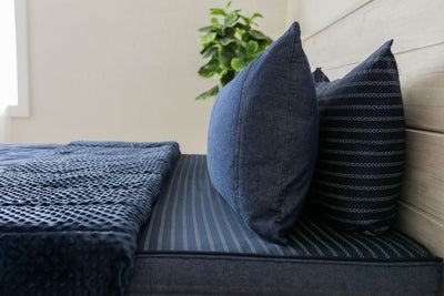 A close up side view of a bed made with dark denim blue zipper bedding with the top unzipped halfway down the bed and the comforter folded down.
