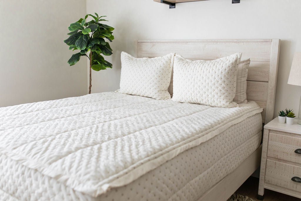 A bed made with cream embroidered zipper bedding with matching pillows.