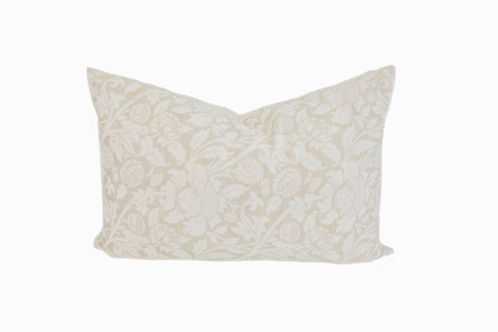 A tan and cream floral design pillow on a white background.