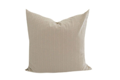 A tan pillow with cream dotted stitching on a white background.