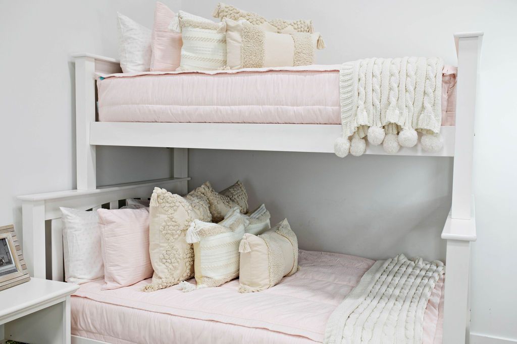 Pink zipper bedding on bunkbed. Deocorated with white, pink, and cream pillows and shams with white and cream throw blankets
