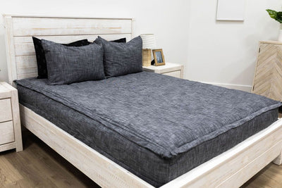 A bed made with dark charcoal gray zipper bedding and matching pillows.