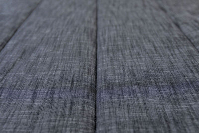 A close up detailed view of a bed made with dark charcoal gray zipper bedding.