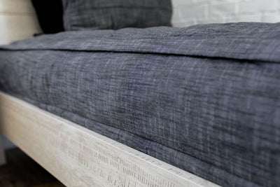 A close up side view of a bed made with dark charcoal gray zipper bedding.