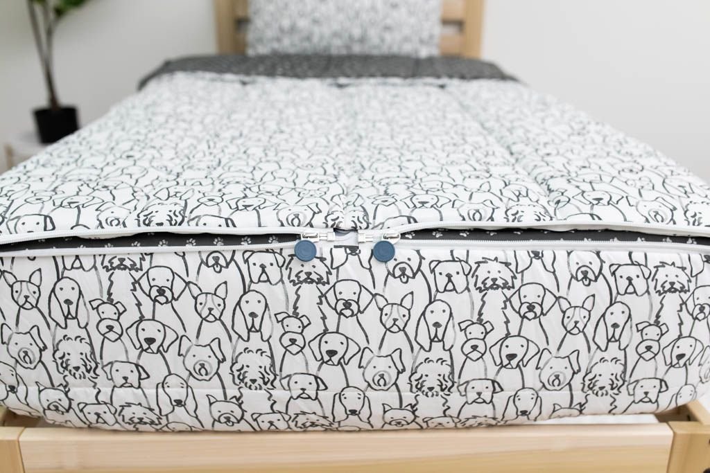 The foot of a bed made with charcoal and white pattern dogs kids zipper bedding showing where the two zippers are located.