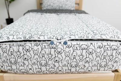 The foot of a bed made with charcoal and white pattern dogs kids zipper bedding showing where the two zippers are located.