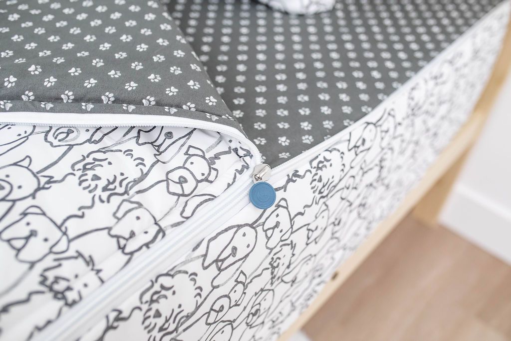 A close up on the zipper feature of a set of charcoal and white pattern dogs kids zipper bedding.