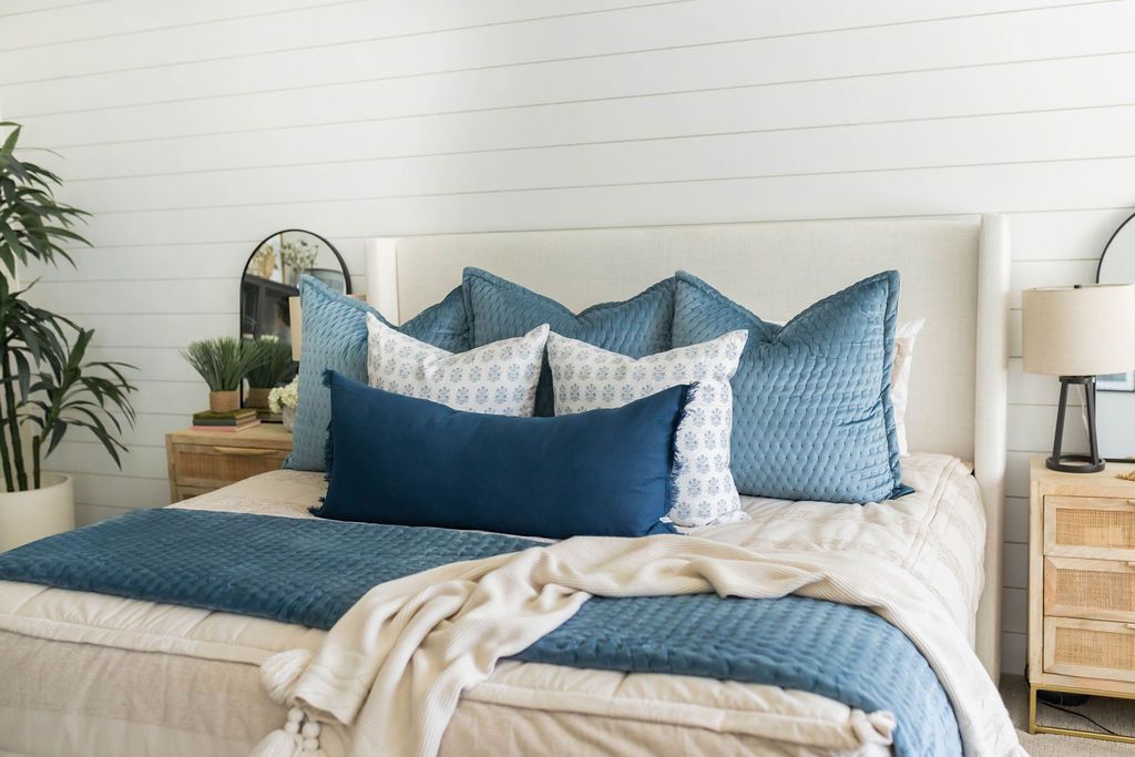 Tan zipper bedding styled with blue, tan and white pillows and tan and blue blankets