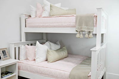 Twin bunk bed styled with pink zipper bedding. Decorated with white, pink and cream pillows and a cream throw blanket