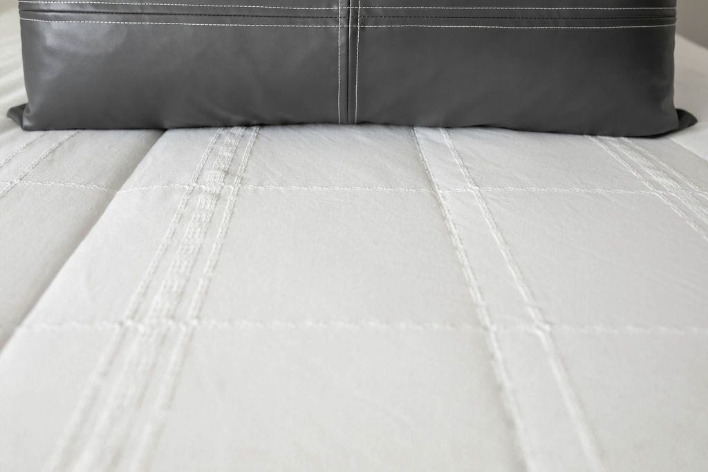 White zipper bedding close up showing bedding texture with black leather lumbar pillow