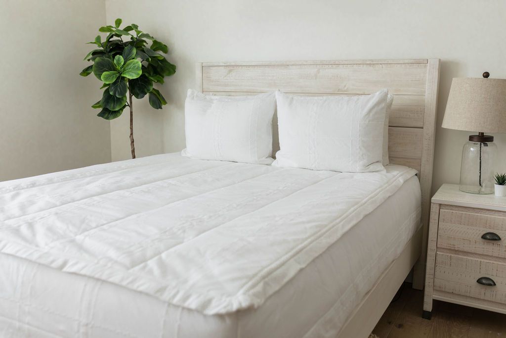 A queen bed made with white woven plaid zipper bedding with matching pillows.