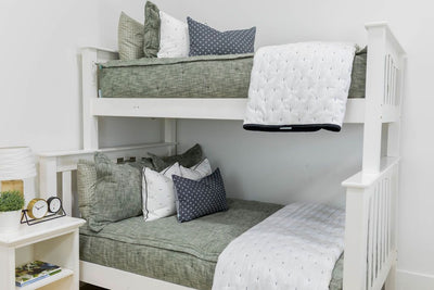 A standard bunk bed with both bunks made with deep emerald green zipper bedding and black and white pattern pillows and blankets.