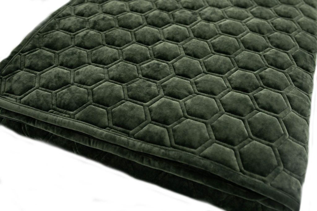 A close up view of a folded emerald honeycomb pattern velvet blanket.