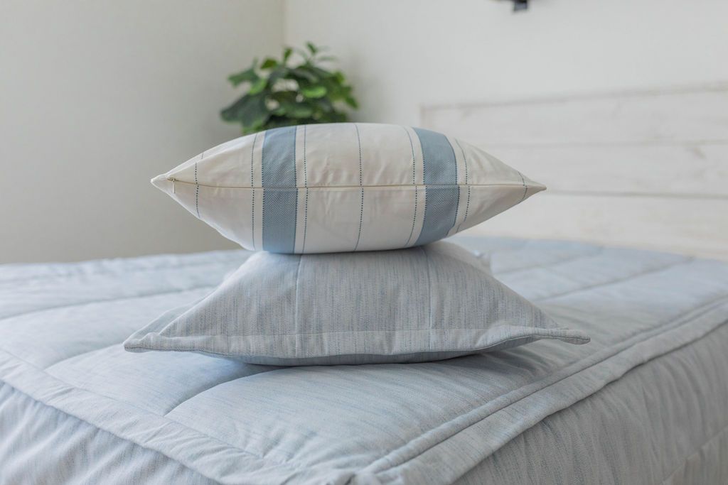 A light blue zipper bedding made with matching pillows stacked in the middle of the bed. 