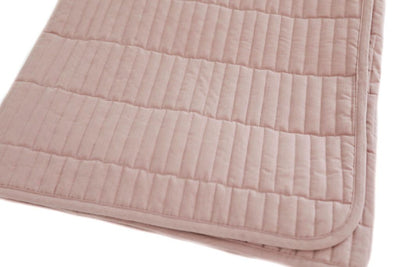 A pink piano key quilted blanket folded together on a white background.