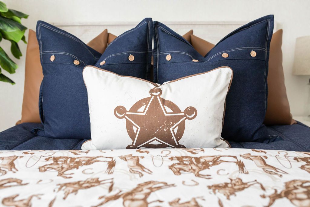 Blue zipper bedding with brown faux leather pillows, blue pillows and cowboy, horseshoe and sheriff pattern blanket and pillow