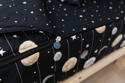 A close up on the zipper feature of a set of black planets and stars kids zipper bedding.