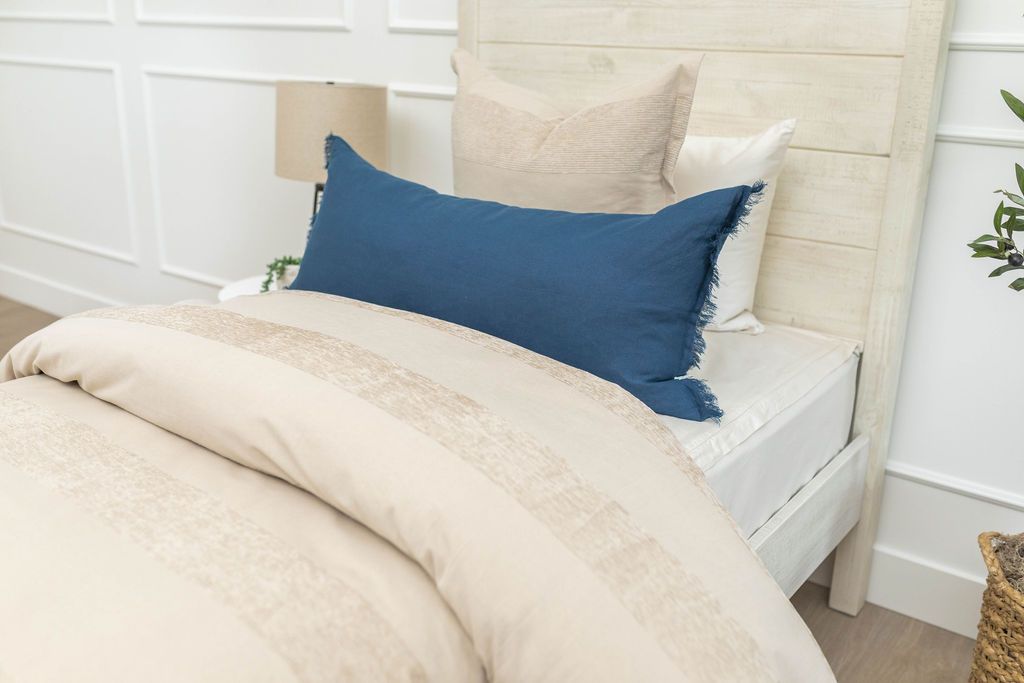 Tan duvet bedding styled with matching euro pillows and blue lumbar pillow