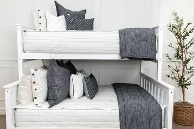 A standard bunk bed with both bunks made with white and pinstripes zipper bedding and white and dark charcoal gray pillows and blankets.