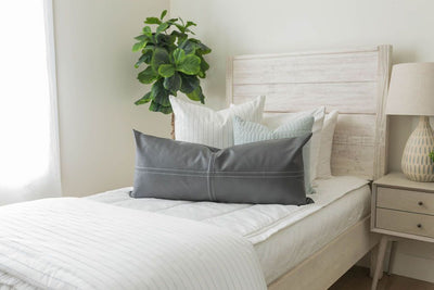 A twin bed made with white woven plaid zipper bedding and an assortment of neutral and striped pillows and matching blanket.