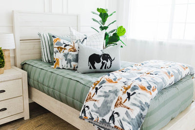 twin bed with Green striped bedding with white and black grid patterned euro, safari animal print pillow, gray lumbar with embroidered elephant and safari animal print blanket