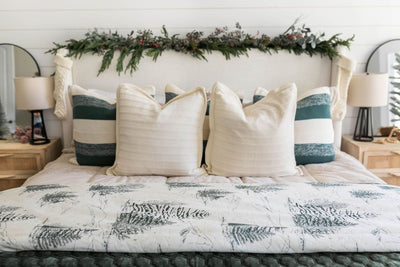 Tan zipper bedding styled with cream and green pillows and white and green forest design blanket