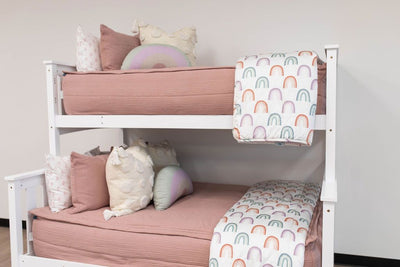 Bunk bed with pink zipper bedding styled with white blanket and pink, cream, and white pillows